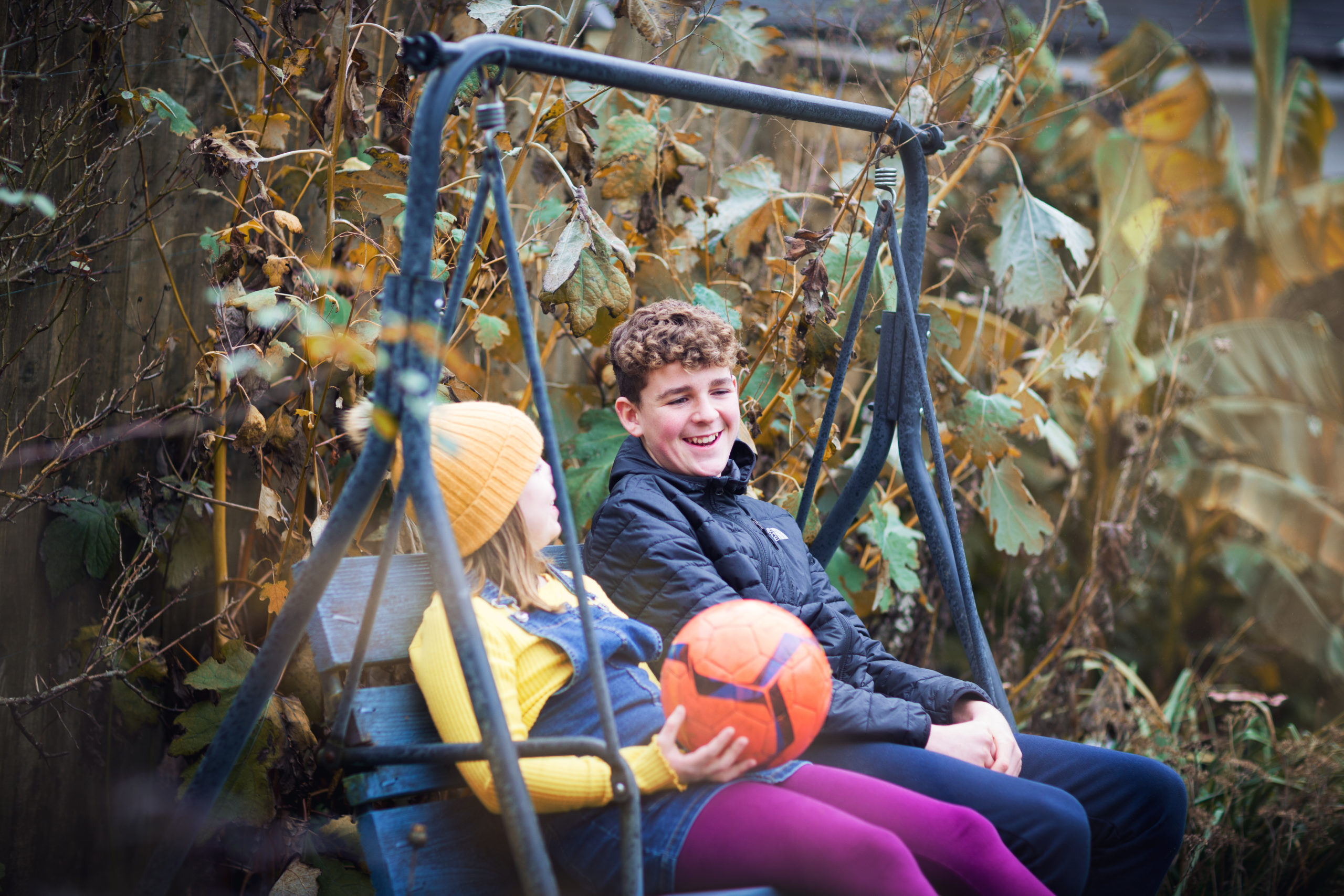 A young girl and a young boy smile as they chat in the garden
